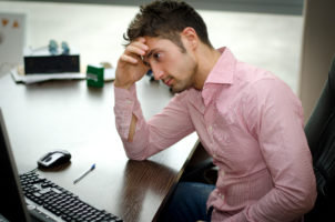 Young male stressed in front of computer